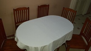 A dining area with a round table covered with a white tablecloth, surrounded by wooden chairs. - Hostel Vienna (Cairo)