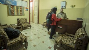 A reception area with patterned sofas, a reception desk, and a bulletin board. - Hostel Vienna (Cairo)