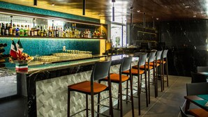 A bar area with a marble countertop, multiple bar stools, and a variety of bottles and glasses.