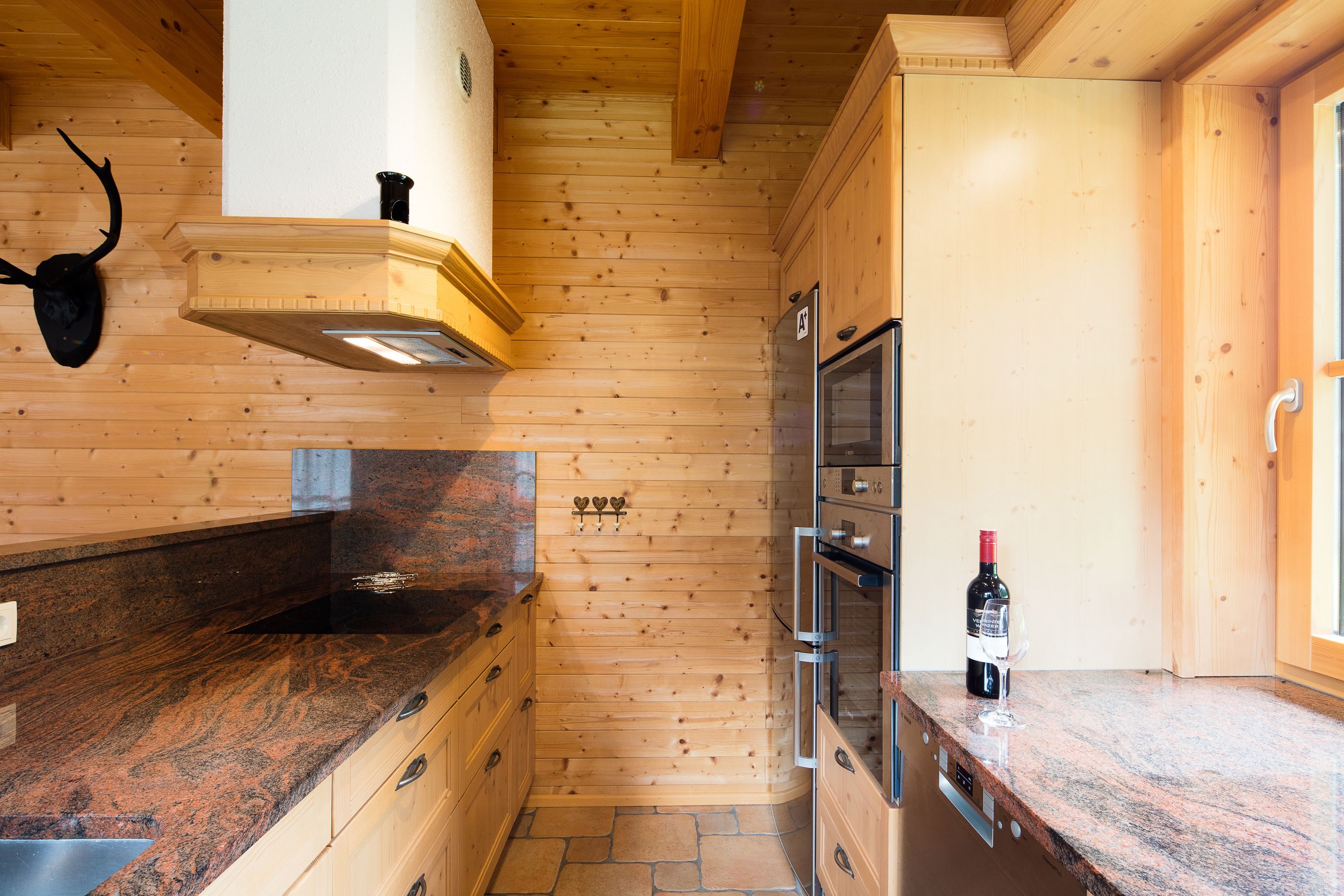 Una cocina con paredes de madera, encimera de granito, estufa y refrigerador.