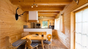 Interno in legno con tavolo da pranzo, sedie, una panca e una testa di cervo appesa al muro.