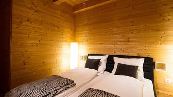 A wooden-paneled room with a bed, two bedside tables, and wall-mounted lamps.
