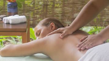 A massage therapy session in a room with a wooden table, towels, and a bamboo backdrop.