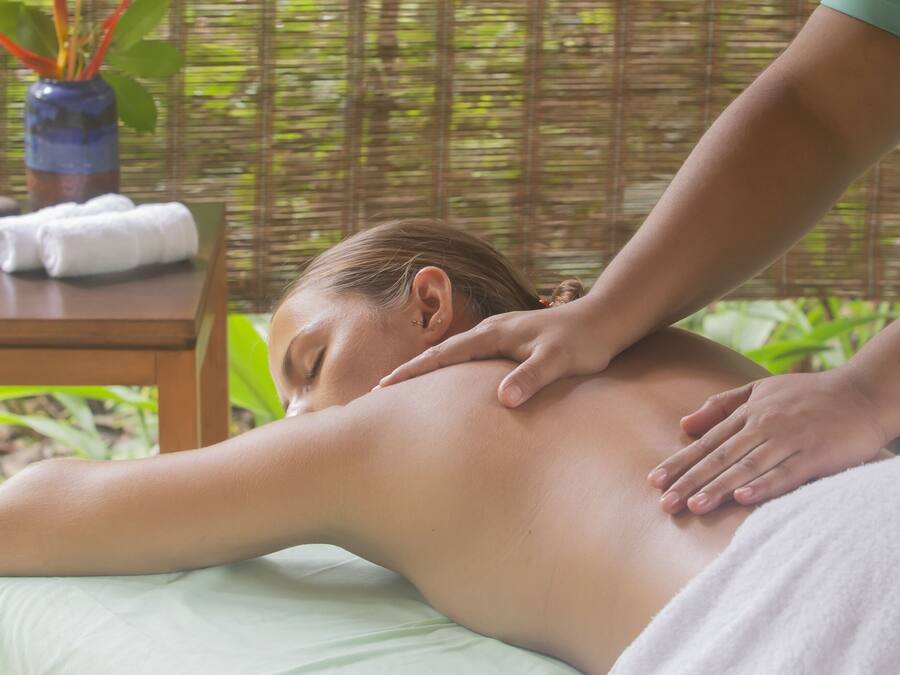 A massage therapy session in a room with a wooden table, towels, and a bamboo backdrop.