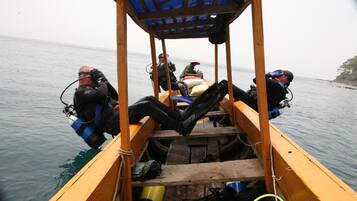 A wooden boat with four divers seated inside, equipped with scuba gear.