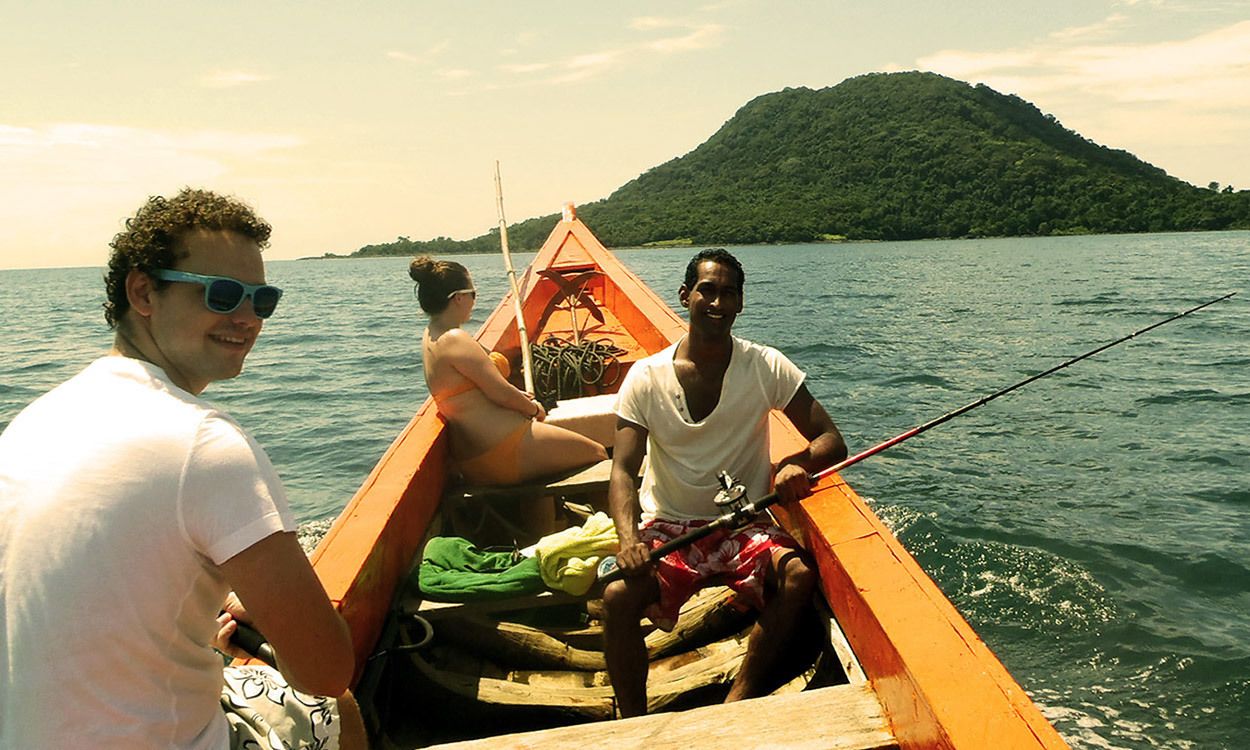 A small wooden boat with two people on it, one holding a fishing rod.
