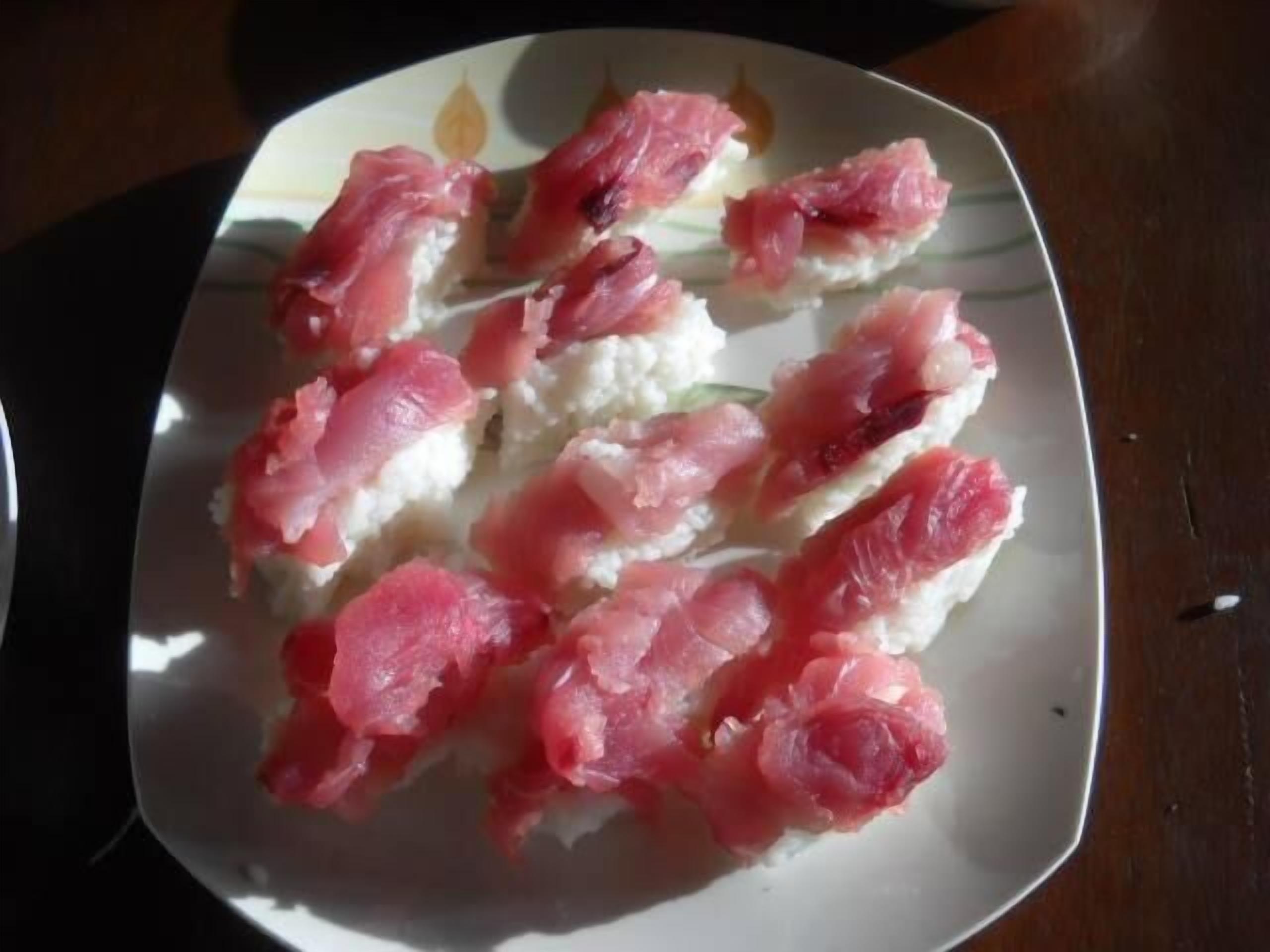 A plate of sushi with pink fish on white rice.