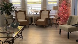 A cozy living room with wicker chairs, a glass coffee table, a pink Christmas tree, and a radiator. - The Baxa Inn (Buckhannon)
