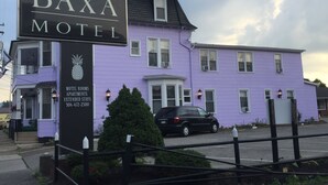 The Baxa Motel with a signboard, a purple building, a black car parked in front, and a small tree. - The Baxa Inn (Buckhannon)