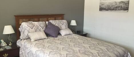 A neatly made bed with patterned bedding, two bedside tables with lamps, and a wall-mounted picture.
