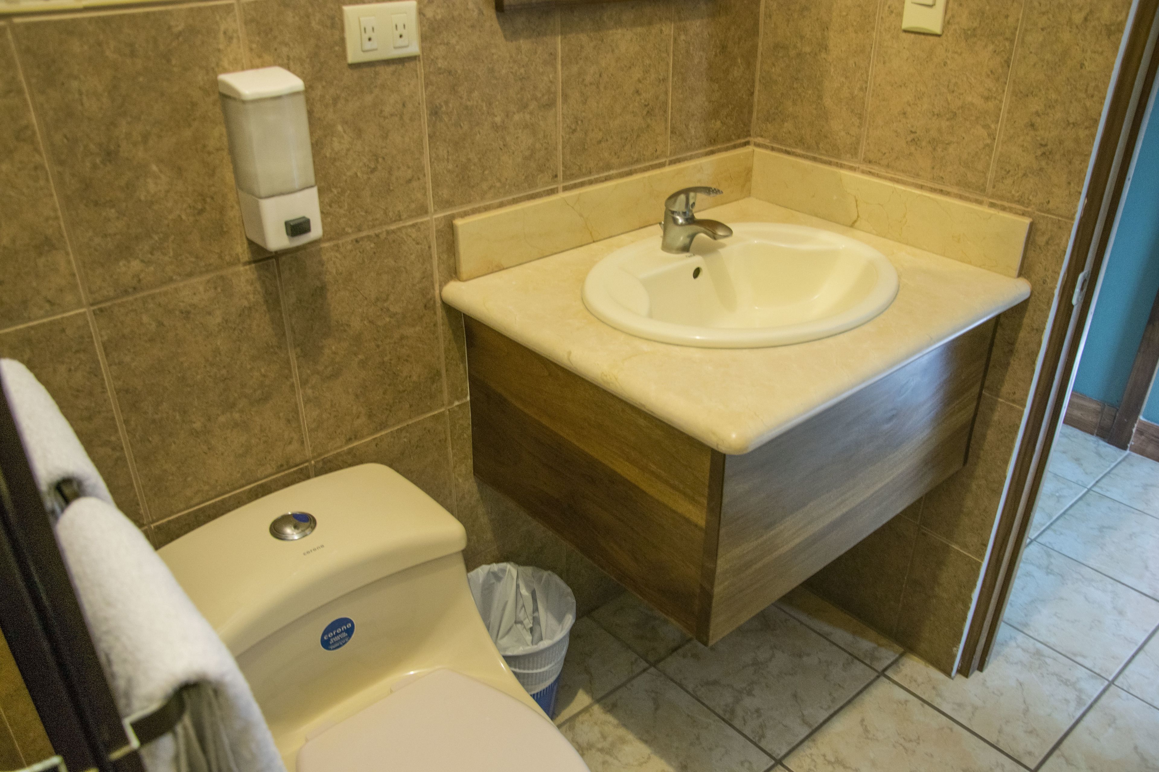Un bagno con un lavandino bianco, un mobile vanitario in legno e un water.