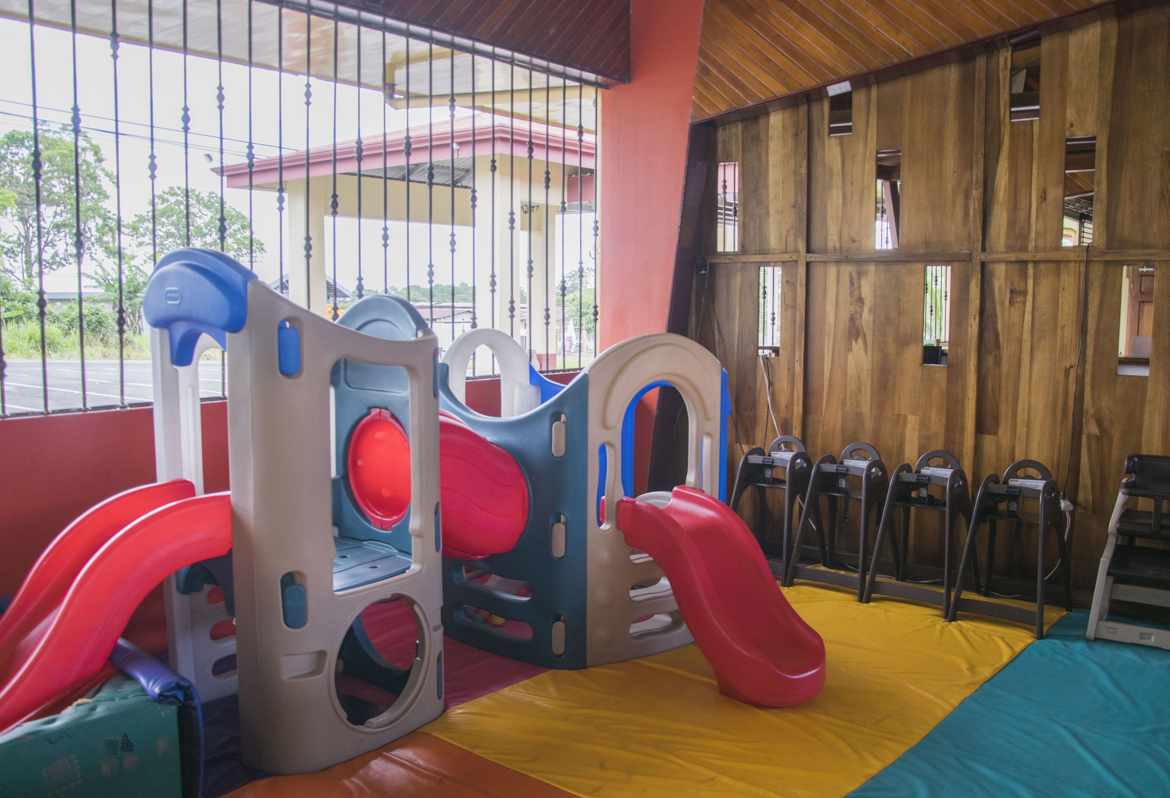 A children's play area with a slide, climbing structure, and exercise equipment.