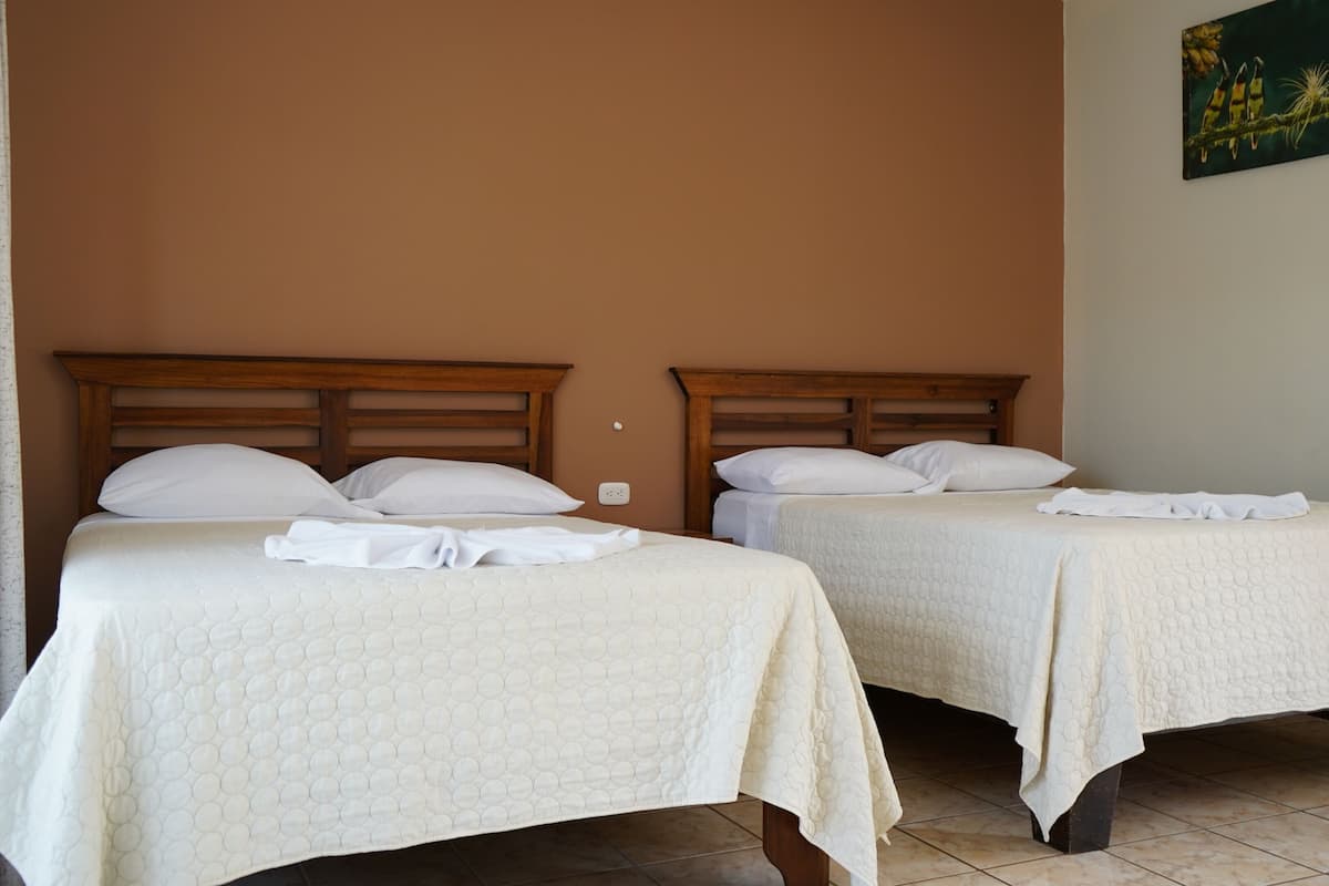 Two single beds with wooden headboards, white bedding, and a painting on the wall.