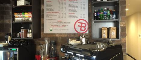 A coffee shop interior with a menu board, espresso machines, and various coffee products on shelves.