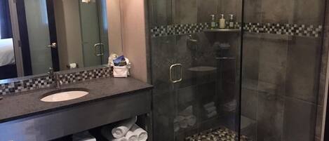 A modern bathroom with a glass-enclosed shower, a double sink vanity, and a tiled backsplash.