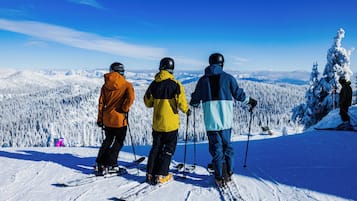 Three skiers on a snowy mountain with a clear sky.