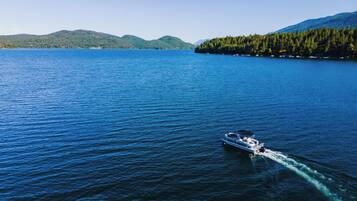 A boat on a calm lake with forested hills in the background.