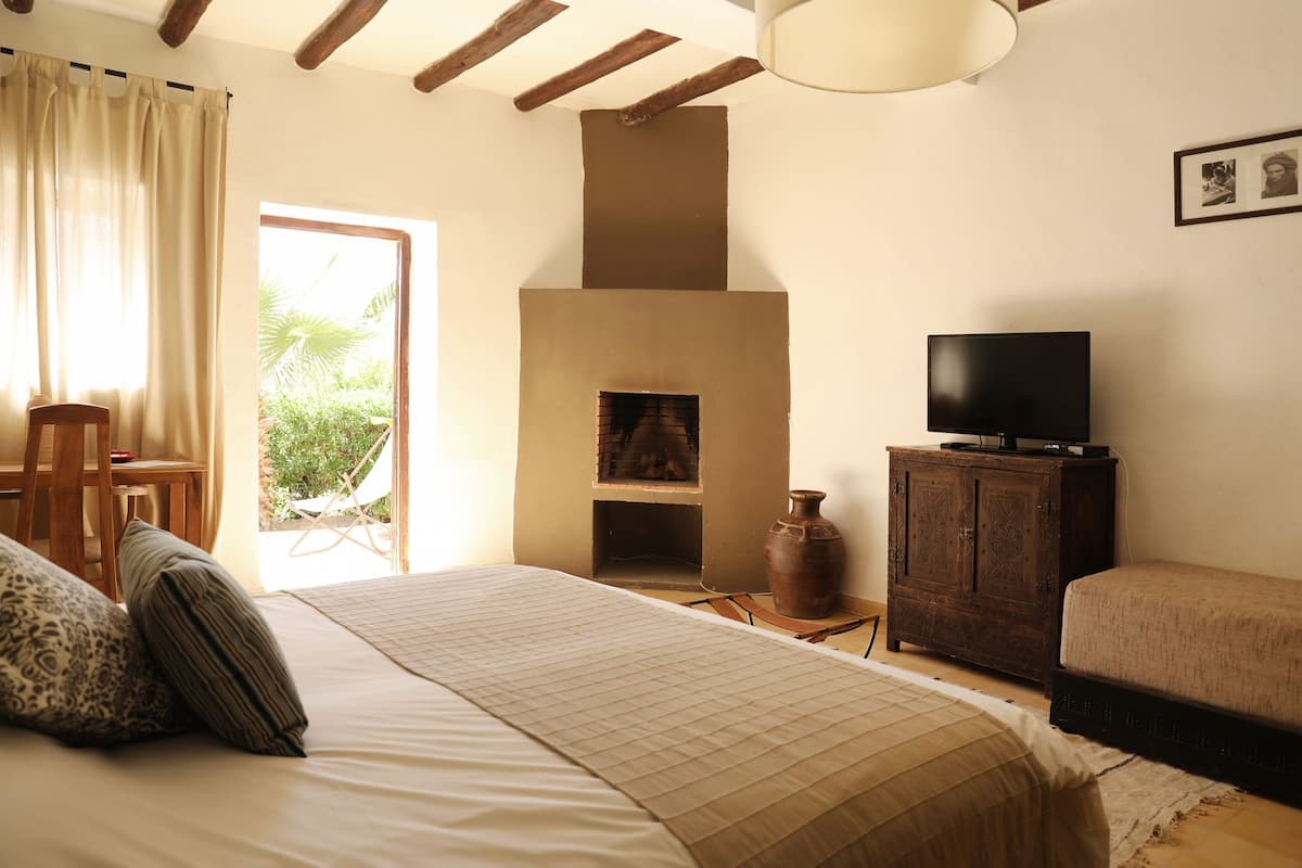 A bedroom with a bed, a television, a cabinet, and a fireplace.