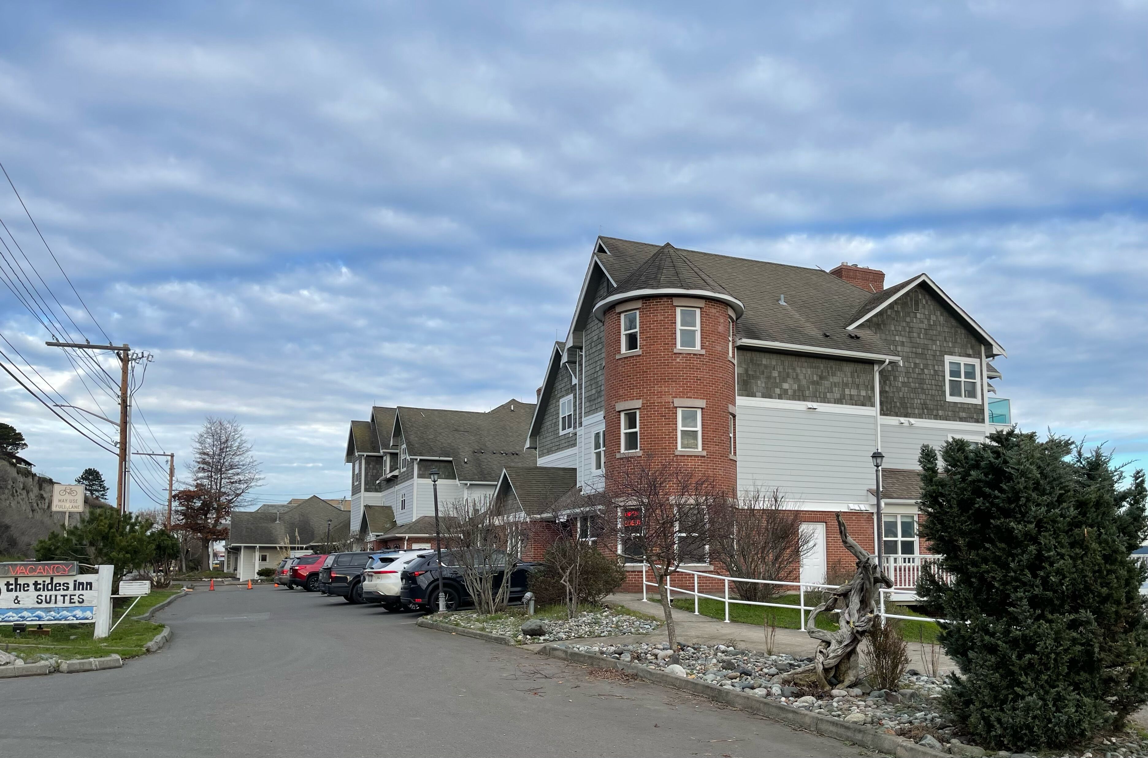 Un immeuble à plusieurs étages dont la façade est un mélange de briques et de bardage, avec un garage et une enseigne indiquant « The Tides Inn & Suites ».