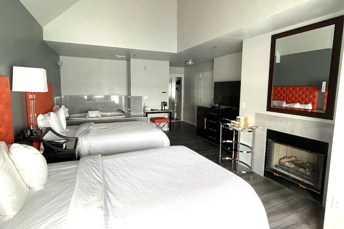 Una habitación de hotel moderna con una cama grande, un escritorio, una silla, un televisor y una chimenea.