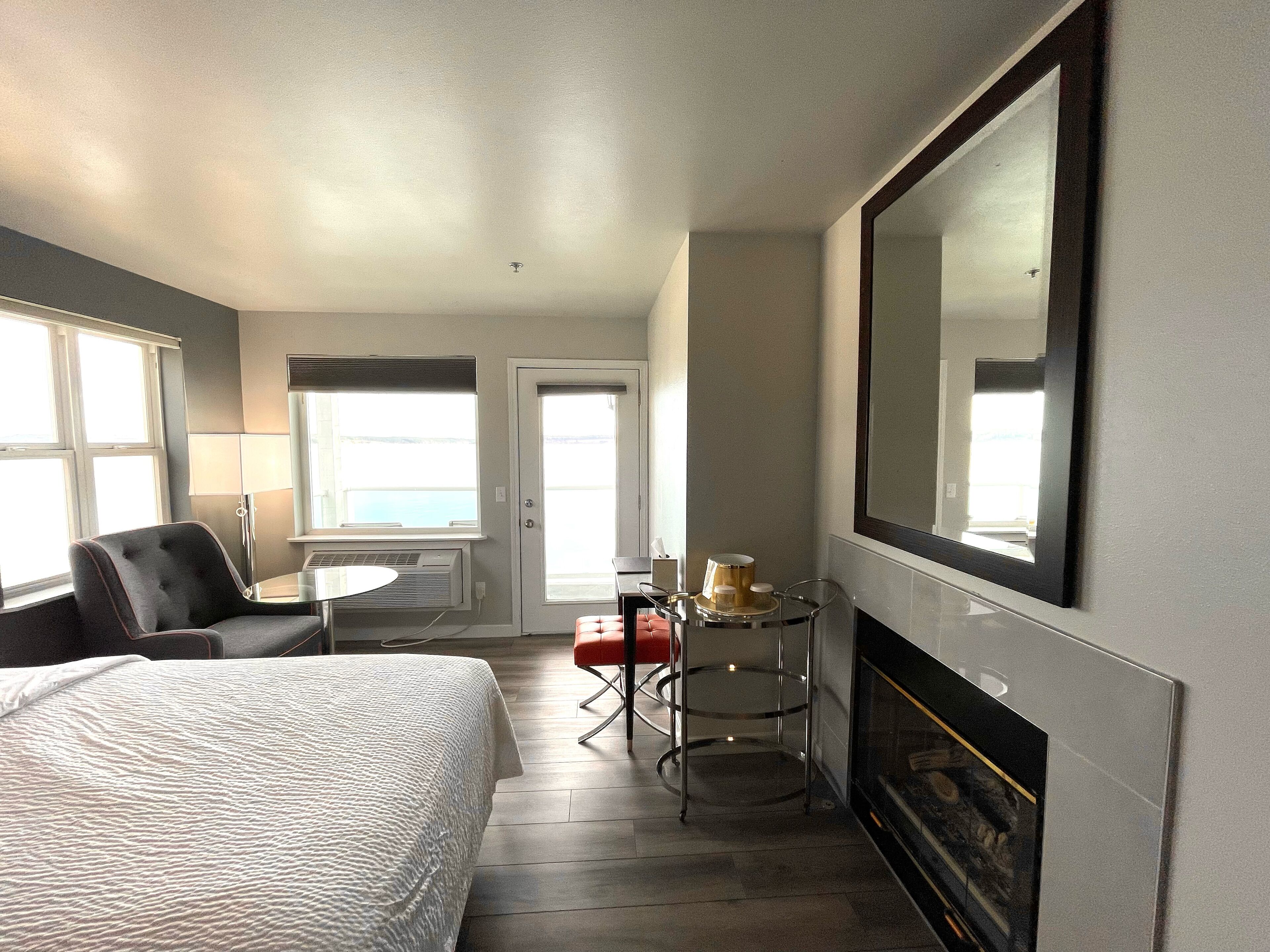 Habitación de hotel con cama, escritorio, silla, mesa con lámpara y chimenea.