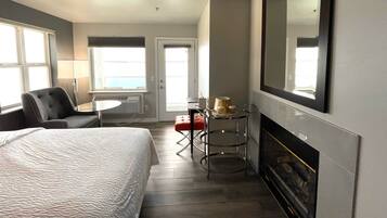 Habitación de hotel con cama, escritorio, silla, mesa con lámpara y chimenea.