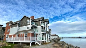 A multi-story coastal building with a balcony, a staircase, and a view of the water. - Tides Inn & Suites (Port Townsend)