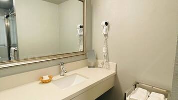 A bathroom with a large mirror, a sink, a hairdryer, and a towel rack.