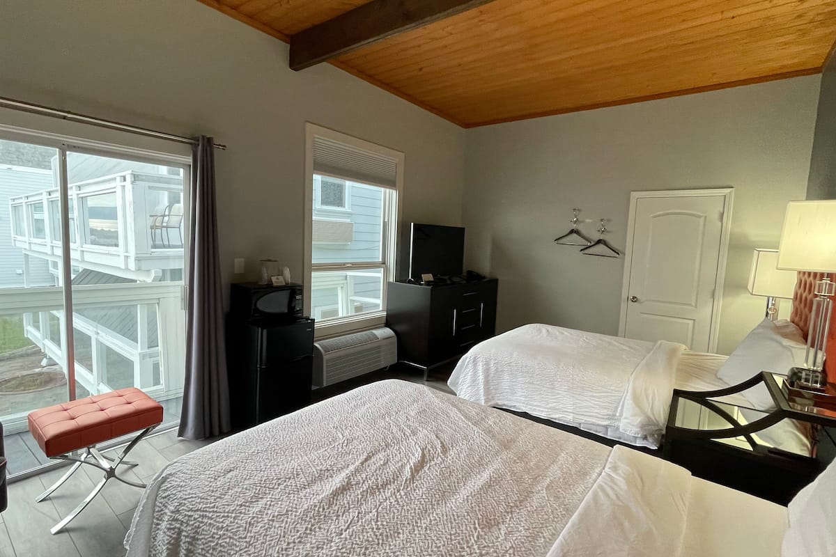 Habitación de hotel con dos camas, un escritorio, una silla, un televisor y vistas al exterior.