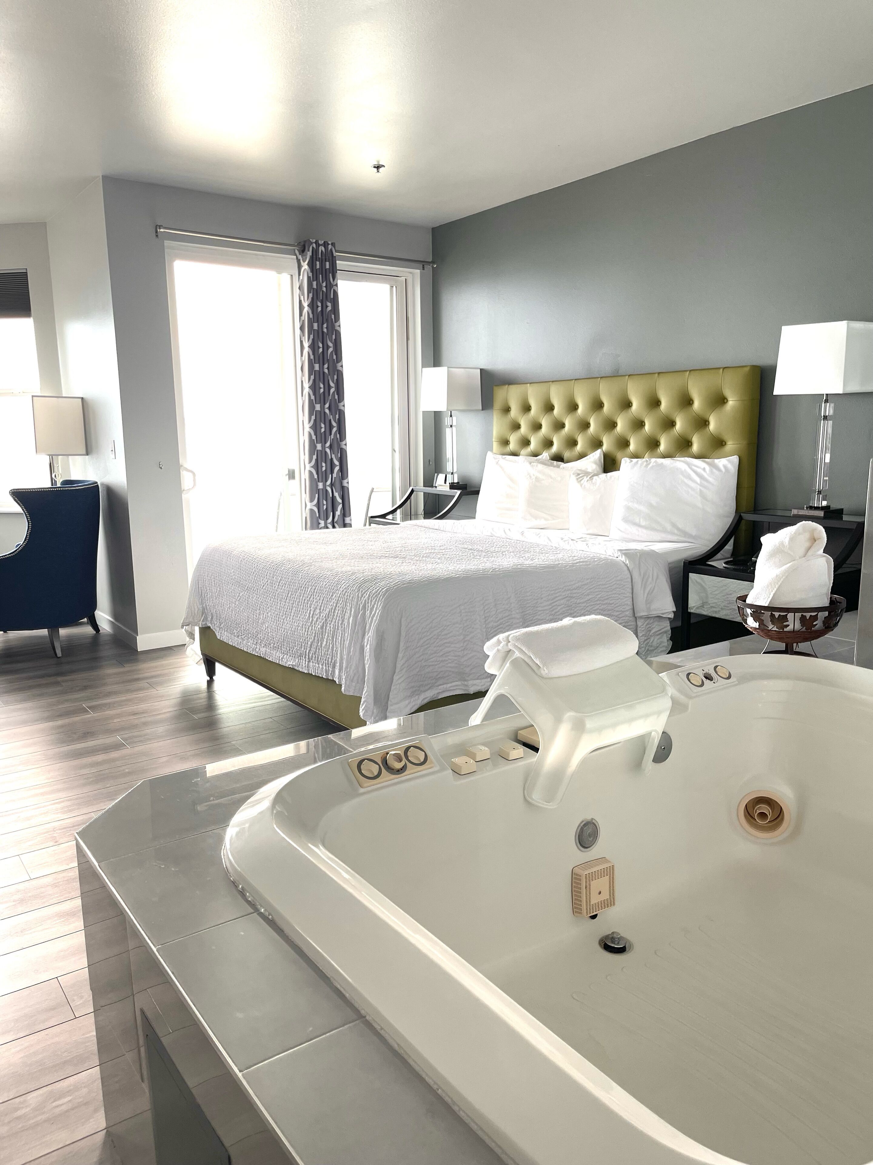 Une chambre d’hôtel dotée d’un grand lit, d’un coin salon séparé, d’une baignoire et offrant une vue sur l’extérieur.