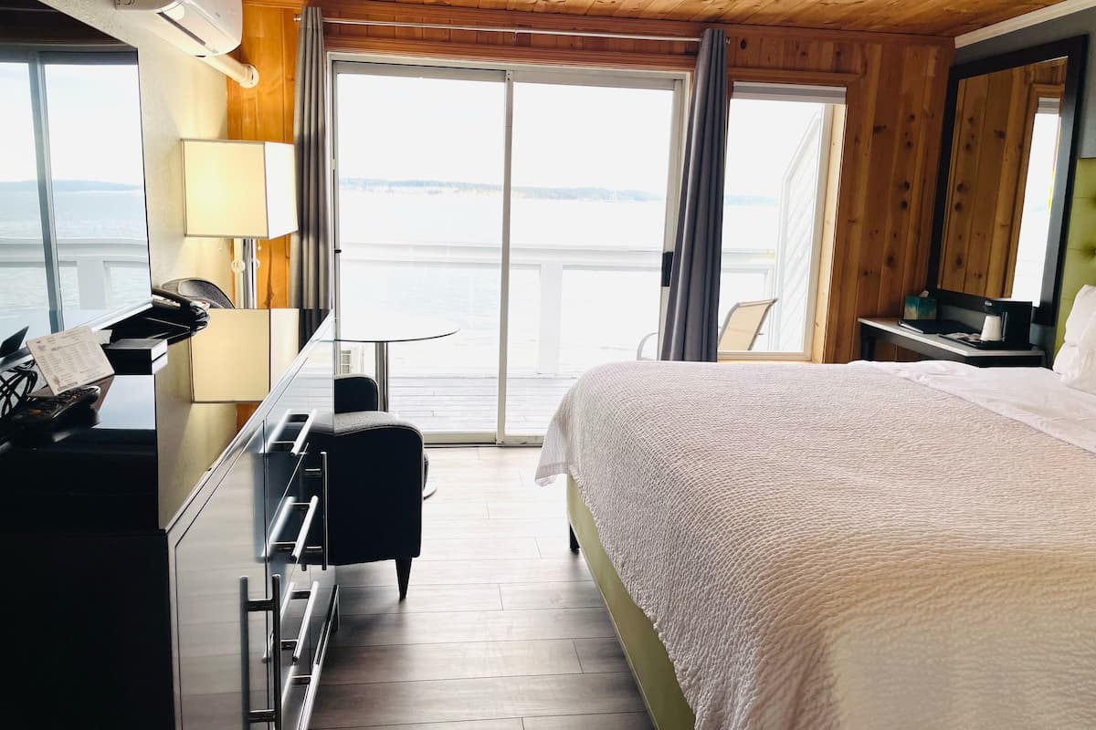 Habitación de hotel con cama, escritorio con computadora, silla y vista al agua.