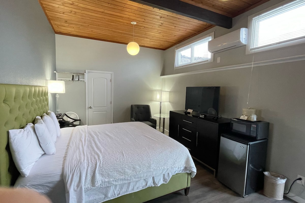 Habitación de hotel con cama, escritorio, televisor y minibar.