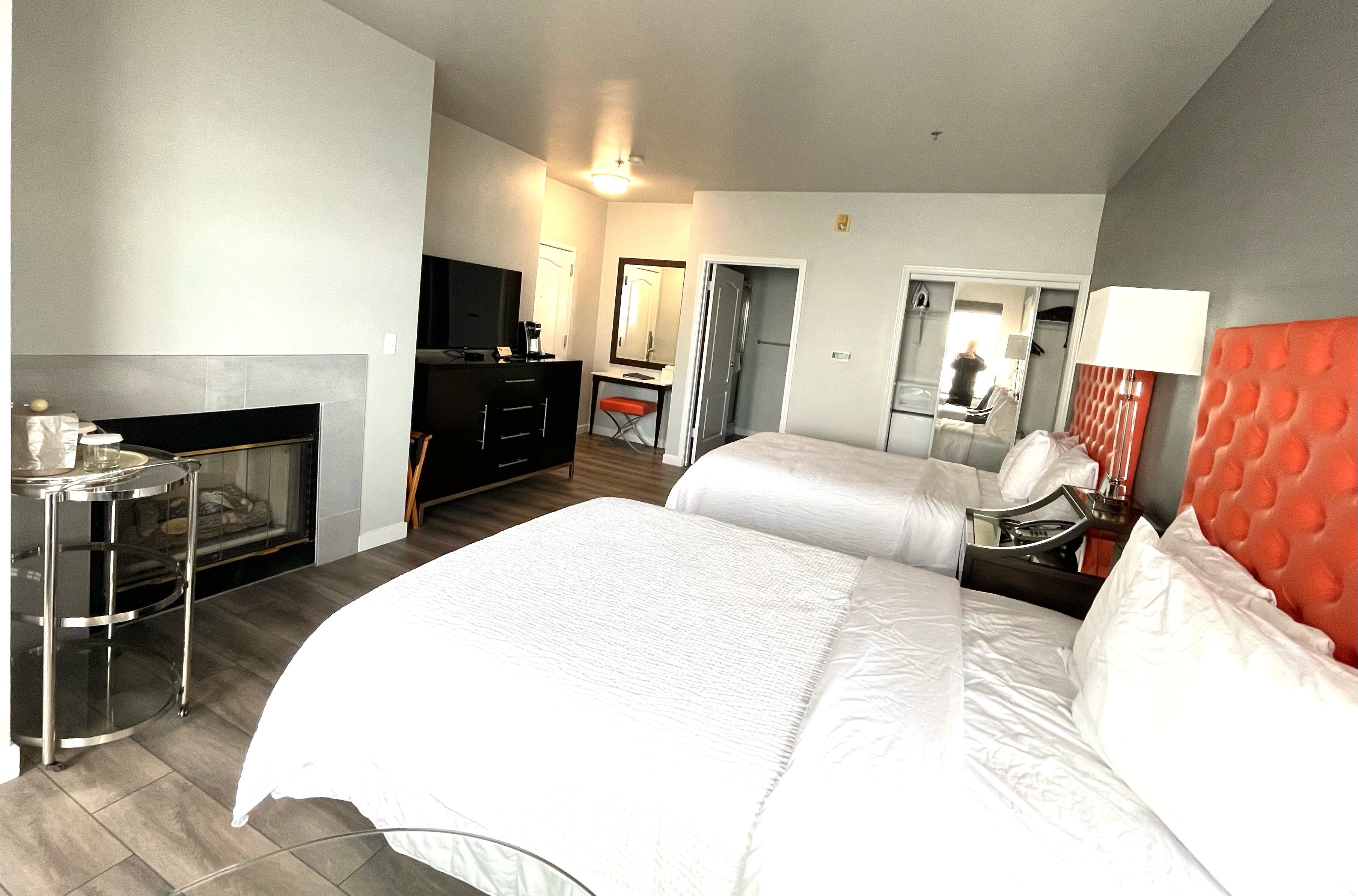 A hotel room with a bed, a desk, a TV, a mirror, and a bathroom.