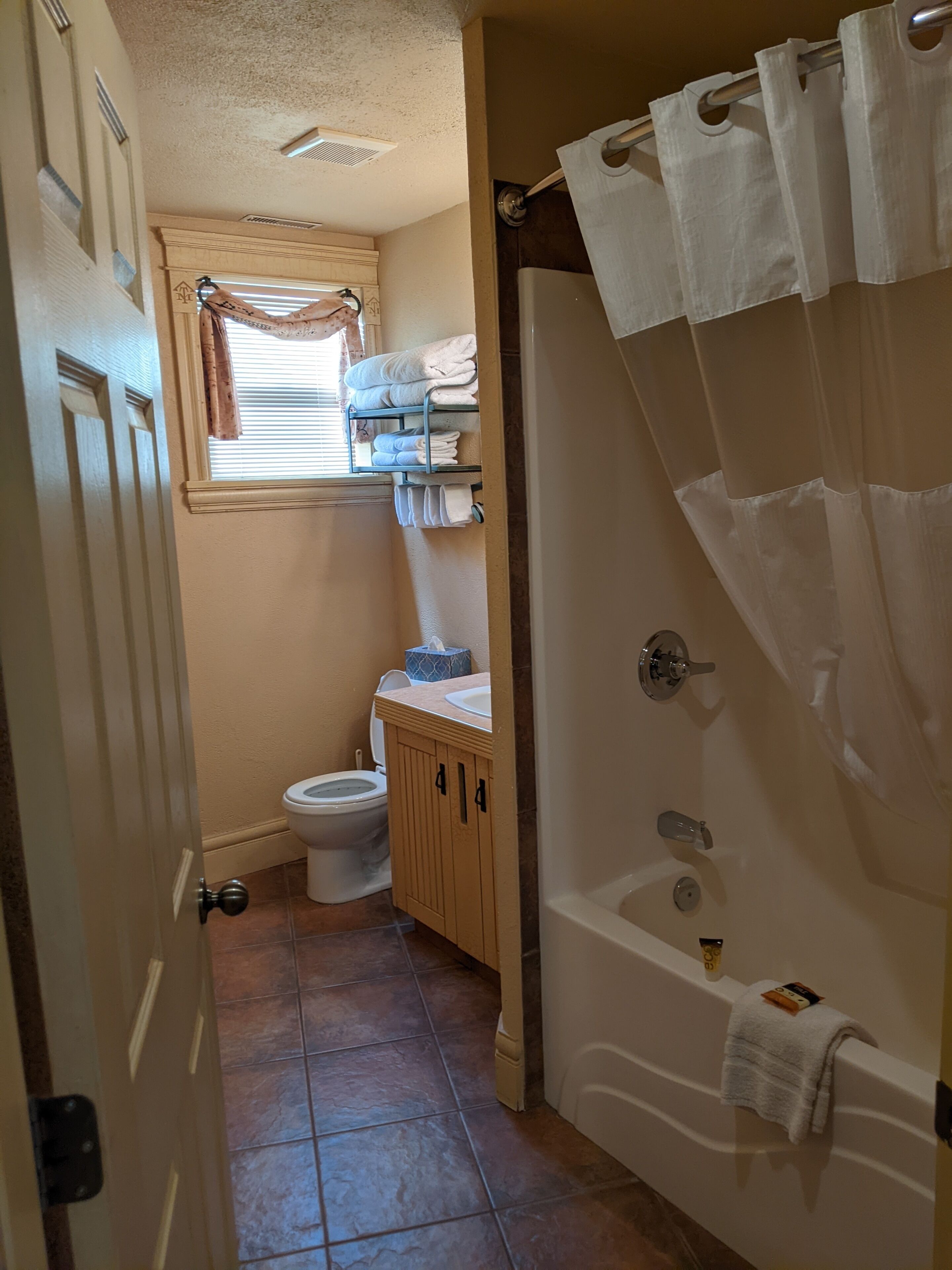 A bathroom with a toilet, a sink, a bathtub, and a shower curtain.