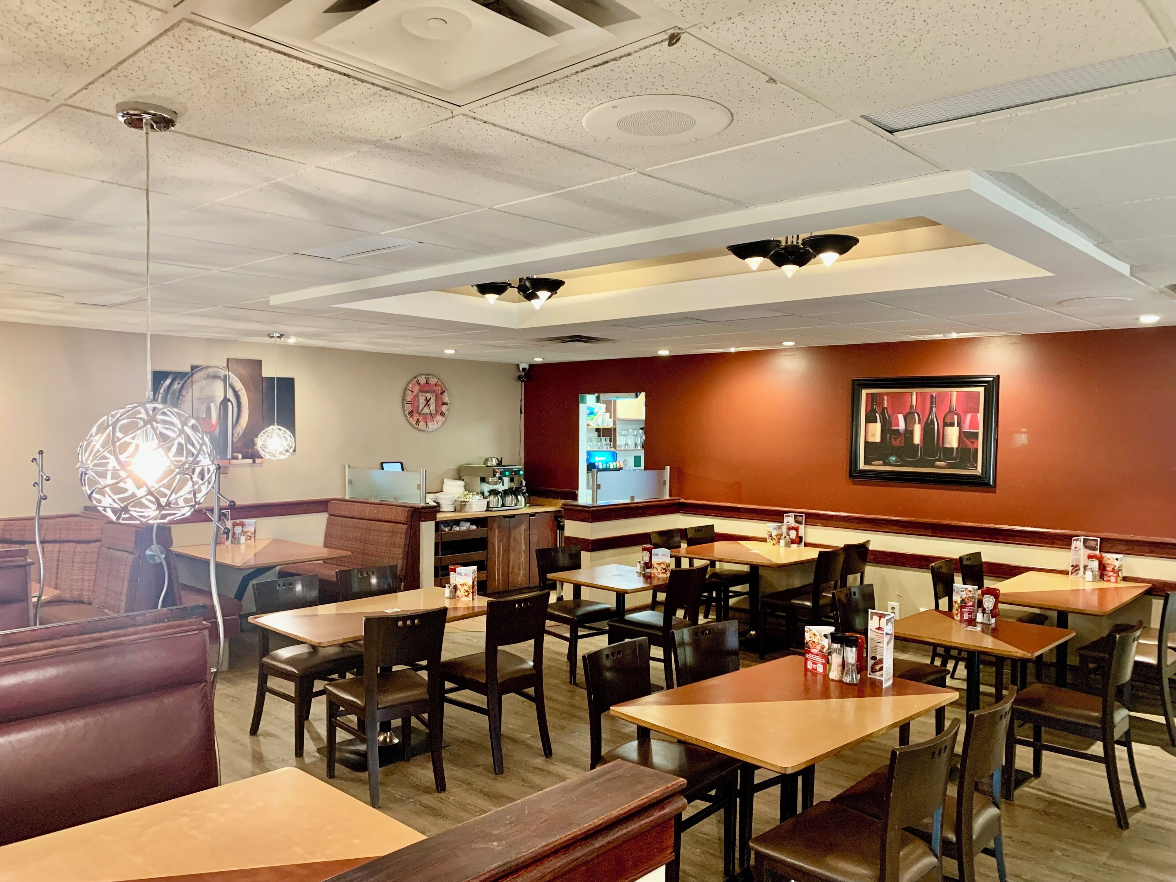 A restaurant interior with booths, tables, and a clock on the wall.