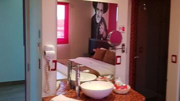 A bathroom with a white sink, a mirror, a hairdryer, and a towel rack.