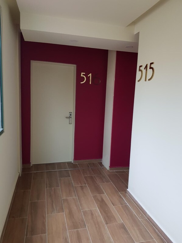 A hallway with a white door, red walls, and floor tiles. Numbers 516 and 515 are visible on the walls.