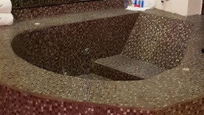 Un baño con lavamanos de mosaicos y un espejo.
