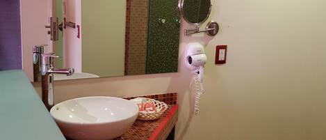 Un baño con un lavamanos blanco, un espejo y un perchero para toallas.