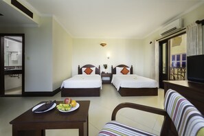 A hotel room with two beds, a dining table with fruit, a TV, and a bathroom visible through an open door. - Sovan Mealea Hotel (Siem Reap)