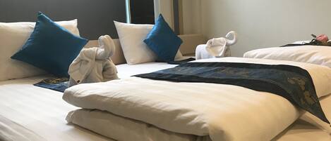 Una habitación de hotel con una cama bien hecha, almohadas y un perchero con toallas.