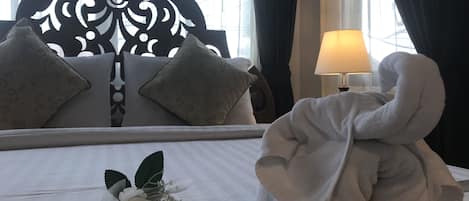 A hotel room with a bed, a bedside lamp, a decorative headboard, and a bouquet of flowers.