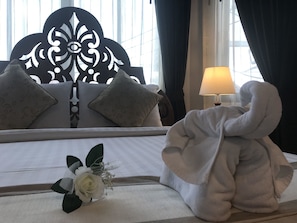 A hotel room with a bed, a bedside lamp, a decorative headboard, and a bouquet of flowers.