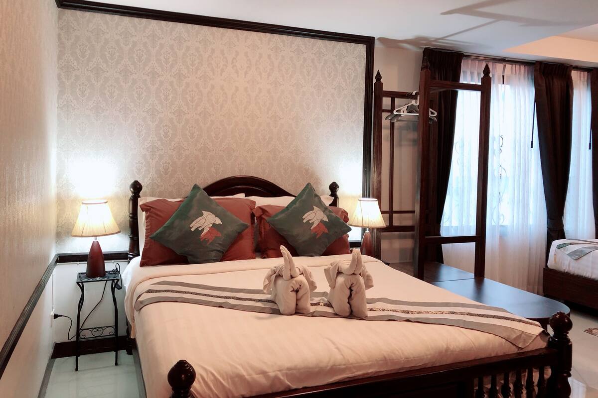 Una cama bien hecha con almohadas decorativas, una lámpara de noche y un arreglo de toallas sobre la cama.