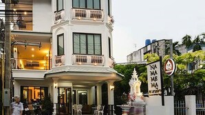 A multi-story building with a prominent entrance, a balcony, and a decorative fountain. - Namamema Boutique Hotel (Chiang Mai)