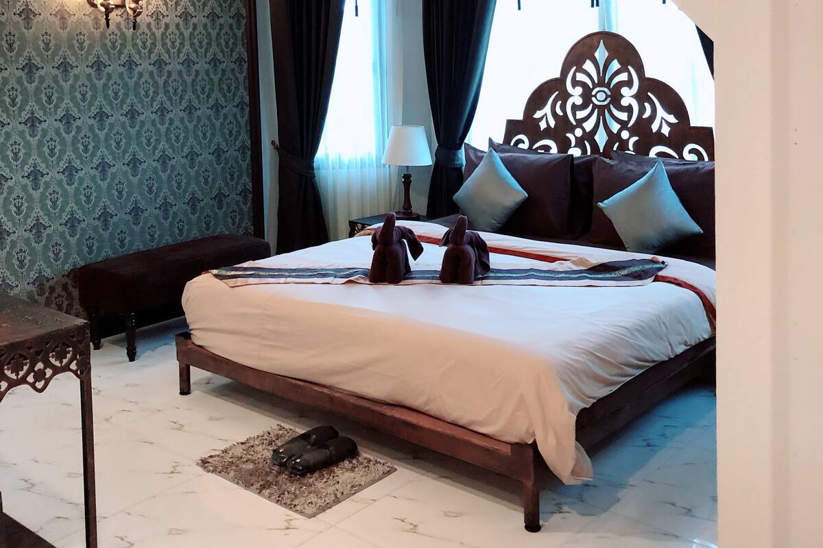 Habitación de hotel con cama, escritorio, silla, lámpara y una escalera.