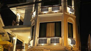 A multi-story building with balconies, a car parked in front, and a person standing near the entrance. - Namamema Boutique Hotel (Chiang Mai)
