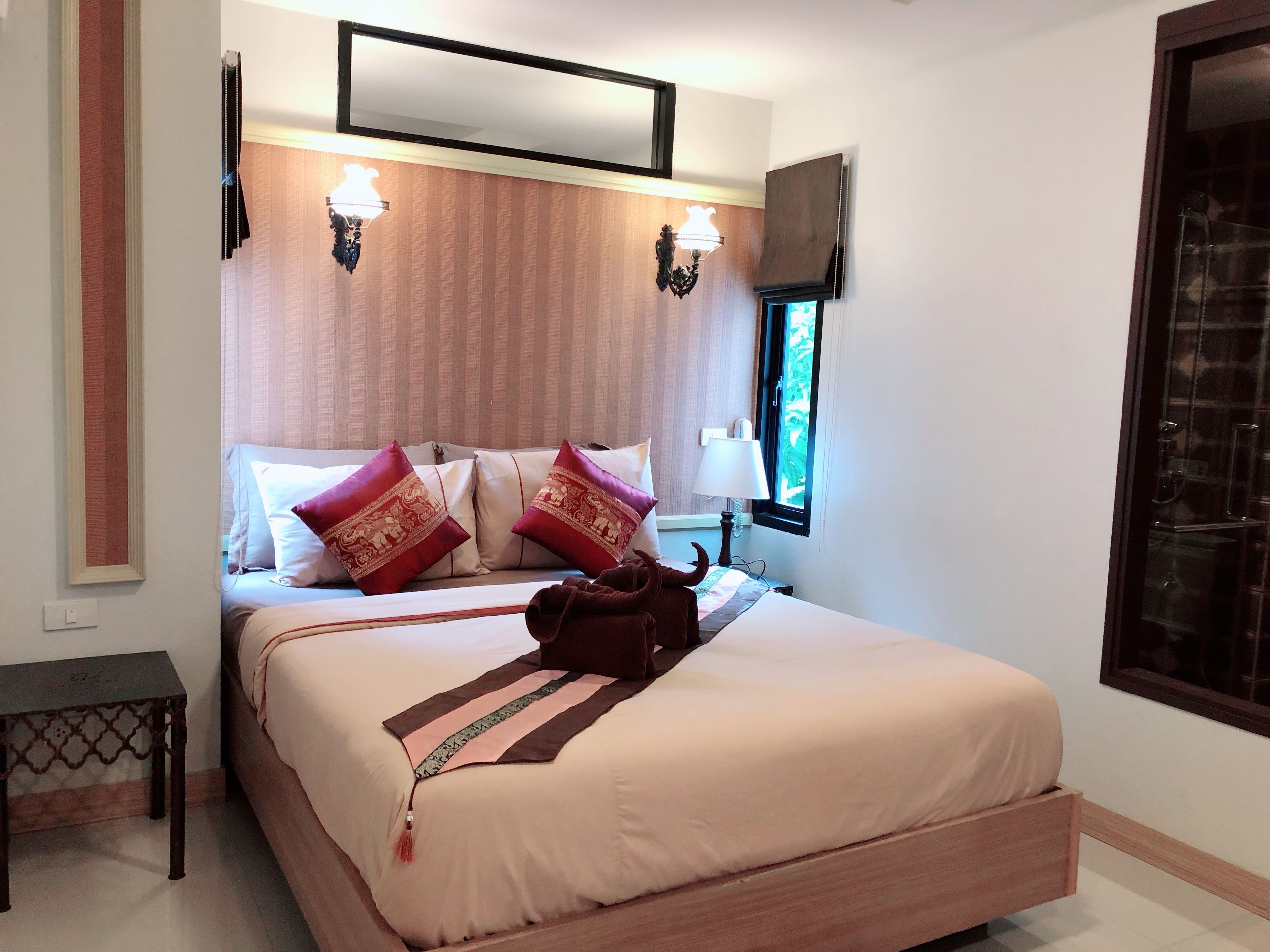 Une chambre à coucher avec un lit, deux lampes fixées au mur, une fenêtre et un miroir.