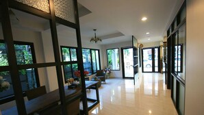 A spacious hotel lobby with a modern design, featuring a wooden reception desk, comfortable seating, large windows, and a chandelier. - Namamema Boutique Hotel (Chiang Mai)