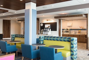Un restaurante moderno con asientos tipo cabina en azul y amarillo, una barra de café y un mostrador con alimentos.